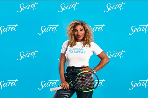 Serena Williams standing smiling holding a tennis racquet