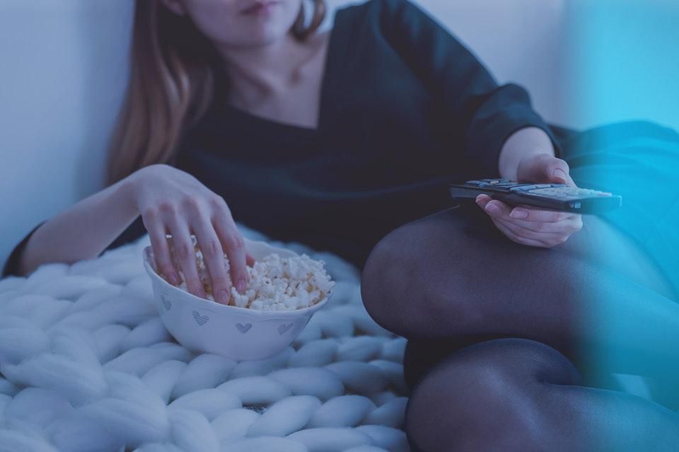 Woman watching tv and eating popcorn