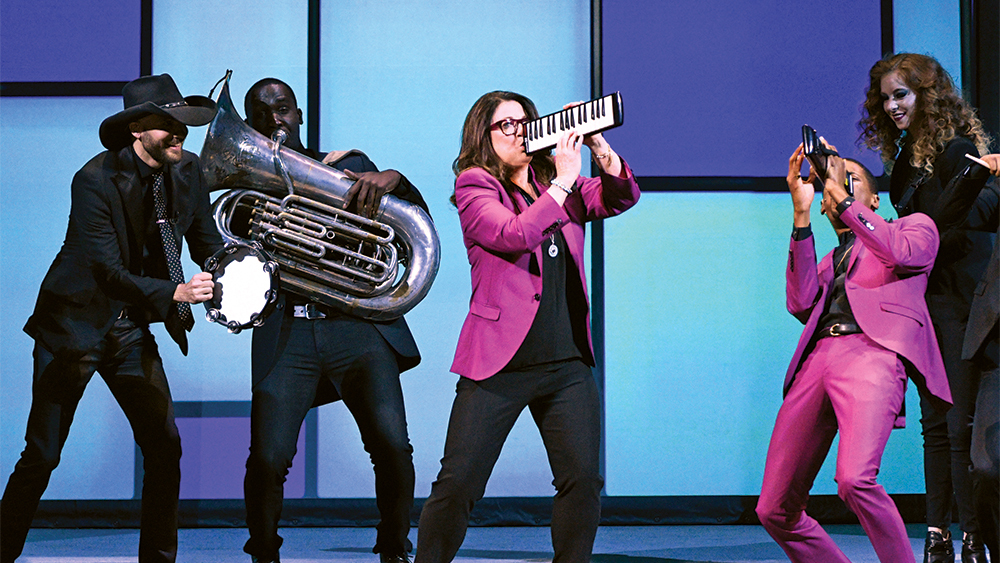 Several people playing instruments on a stage in hot pink suits